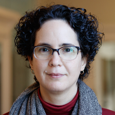 A woman with curly dark hair and glasses
